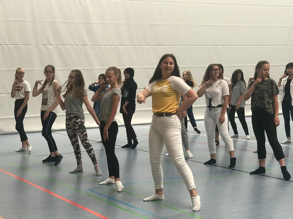 Tanzgruppe probt in Reihen in der Sporthalle.
